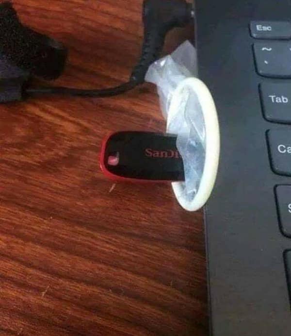A USB flash drive inserted into a laptop port with a condom stretched over the drive.
