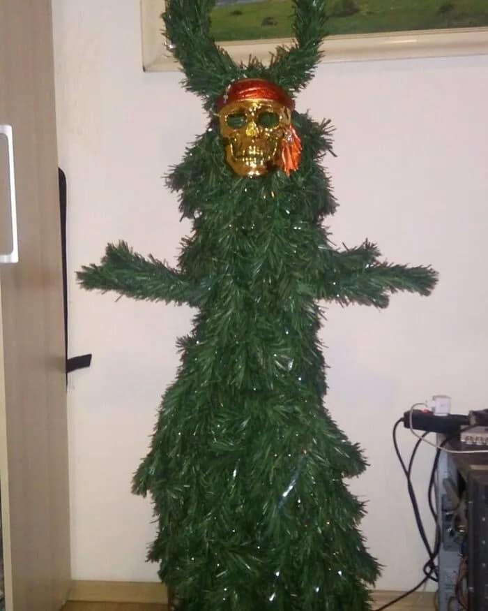 A cursed image showing a bizarre Christmas tree decorated with a pirate skull mask and bandana.