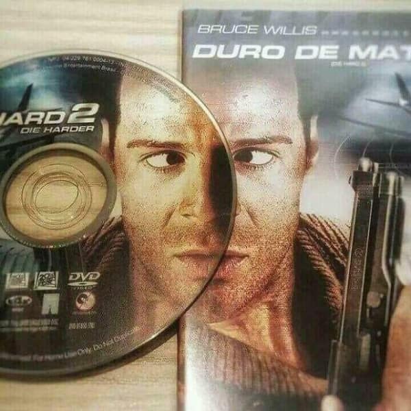 A funny cursed image where the hole in a Die Hard 2 DVD gives Bruce Willis on the cover a perfectly placed googly eye.