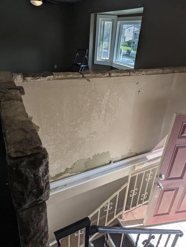 A DIY fail showing a half-demolished wall that has revealed a bizarre interior window overlooking the home's entryway.