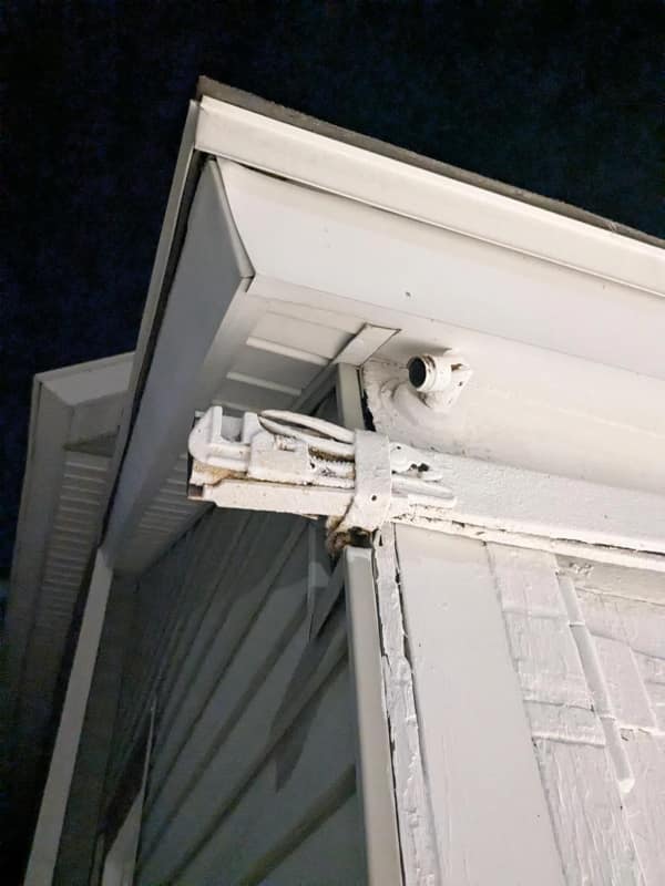 A dangerous home renovation fail showing a jumble of exposed electrical wiring on the outside of a house, all painted white.