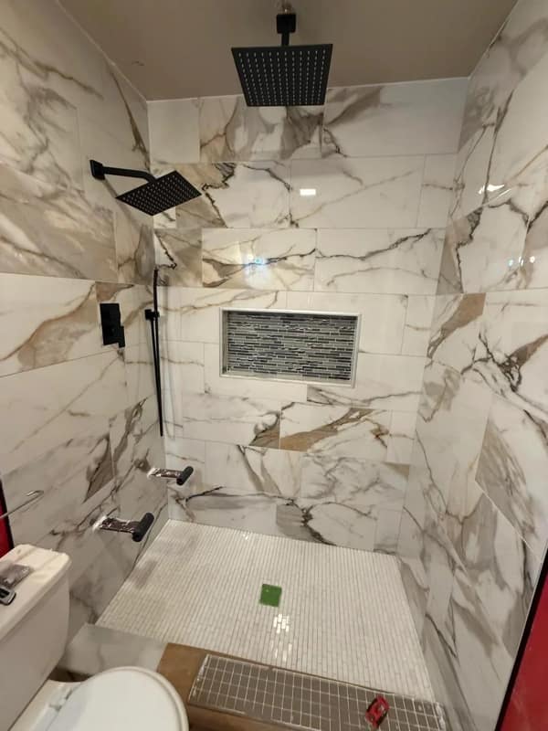 A home renovation fail of a beautifully tiled shower where the small foot rests are installed at shin height.