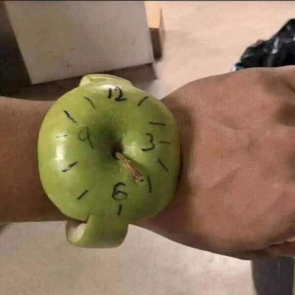 A cursed food image of an "Apple Watch" that has been carved out of a real green apple.