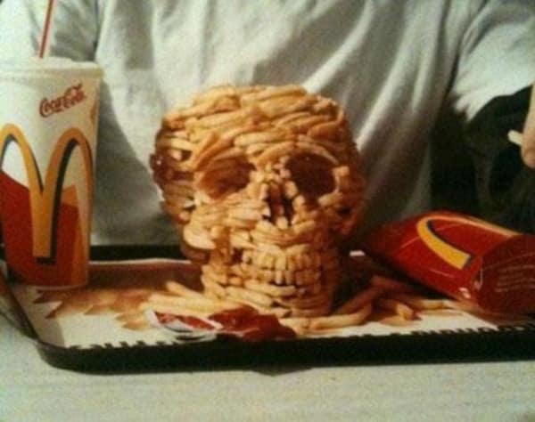A cursed food image of a skull made entirely out of McDonald's french fries on a tray.