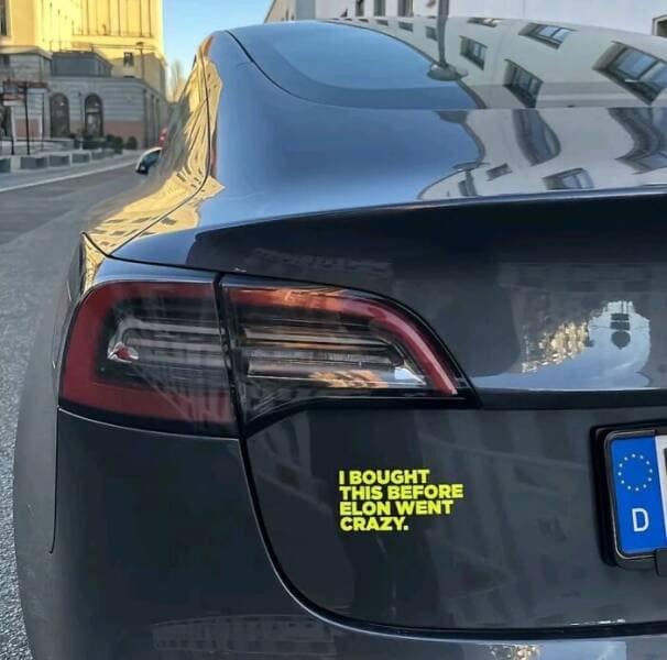 A funny bumper sticker on the back of a Tesla that says, "I bought this before Elon went crazy."