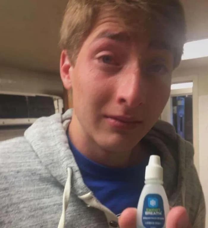 Funny fail photo showing a young man crying after mistaking breath drops for eye drops