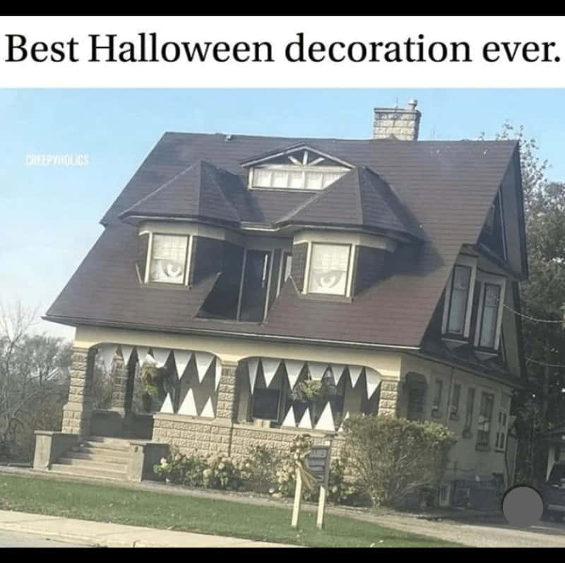 A picture of a house cleverly decorated to look like a monster, with window eyes and a porch mouth full of teeth.