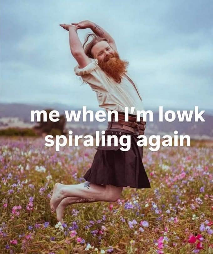 A man with a red beard joyfully jumping in a flower field, ironically captioned "me when I'm lowk spiraling again."