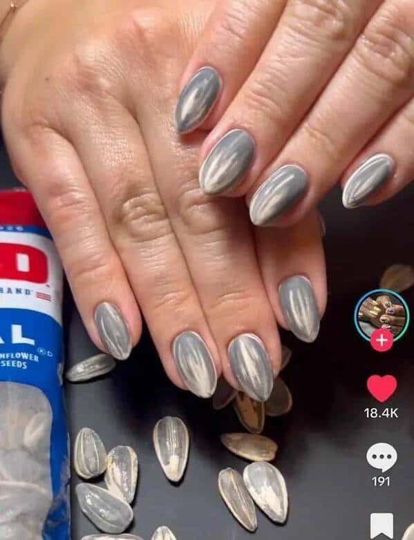 A picture of fingernails painted perfectly to resemble grey and white sunflower seeds.