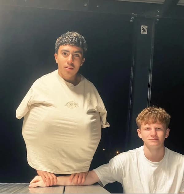 A strange and surreal photo of a person posing in an oversized t-shirt, making them look like a thumb person.