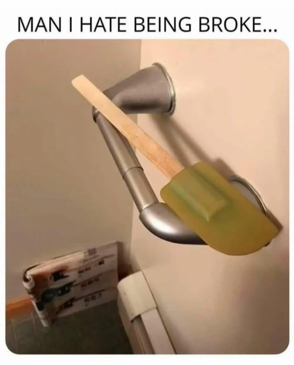 A funny picture of a kitchen spatula being used as a toilet paper holder.