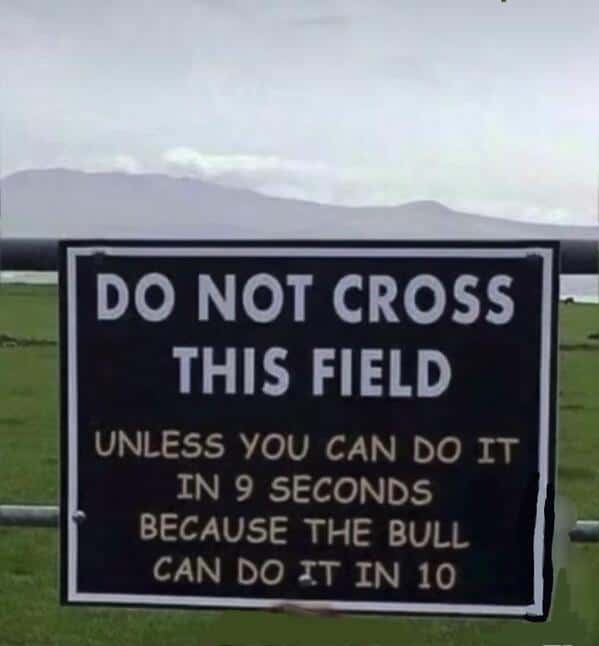 A warning sign advising not to cross a field unless you can beat the bull in a race.