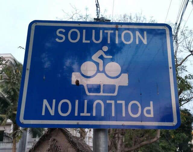 Clever sign design showing a bicycle riding over a car, illustrating pollution and solution