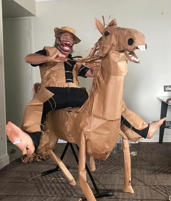 A hilarious meme of a man in a full cowboy and horse costume made entirely out of brown paper bags.