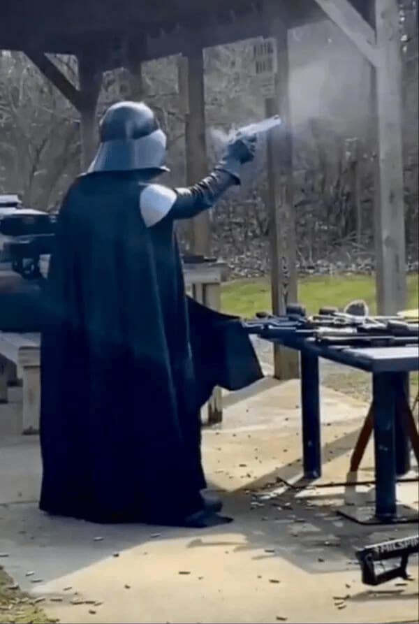 A bizarre no context image of someone in a Darth Vader costume at a gun range.