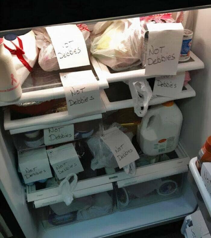 An office refrigerator where every single item is labeled with a handwritten "NOT Debbie's" note.