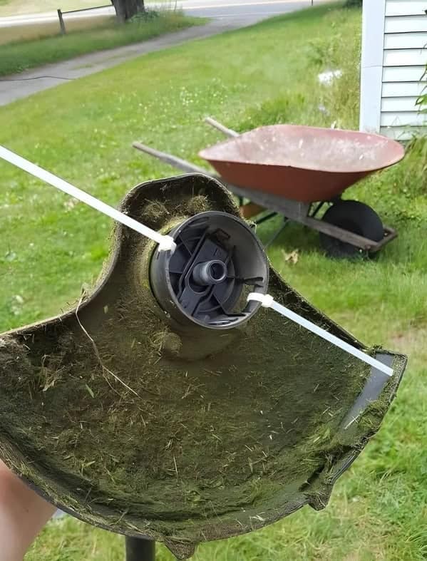 A piece of redneck innovation showing a weed whacker that has been "repaired" by using heavy-duty zip ties instead of string.