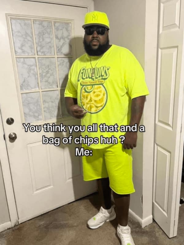 A man confidently posing in a bright neon yellow outfit themed entirely around Funyuns onion rings.