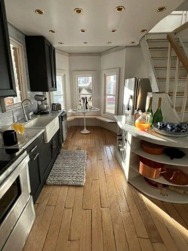 A tiny, realistic dollhouse kitchen with a camouflaged cat peering from the window.