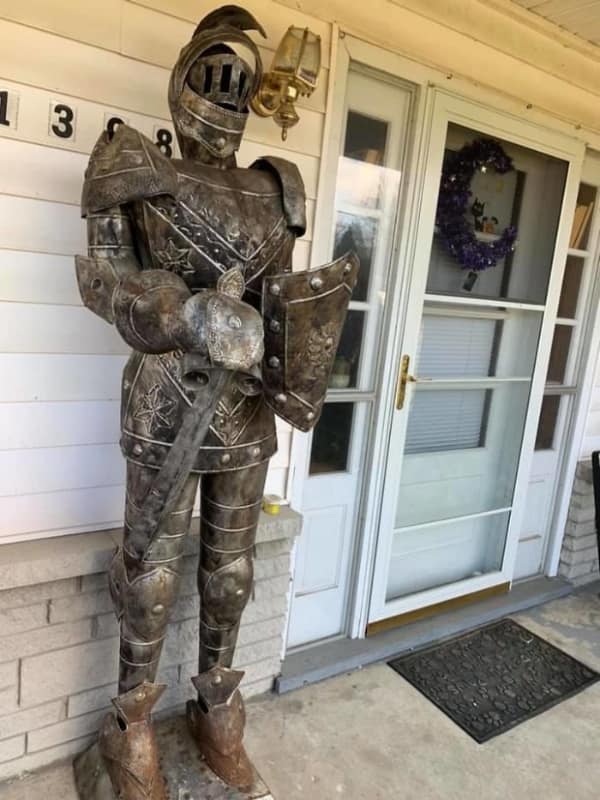 Full size medieval suit of armor standing guard on a residential front porch.