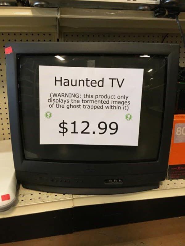 Vintage CRT television with a warning sign claiming it is a haunted object.