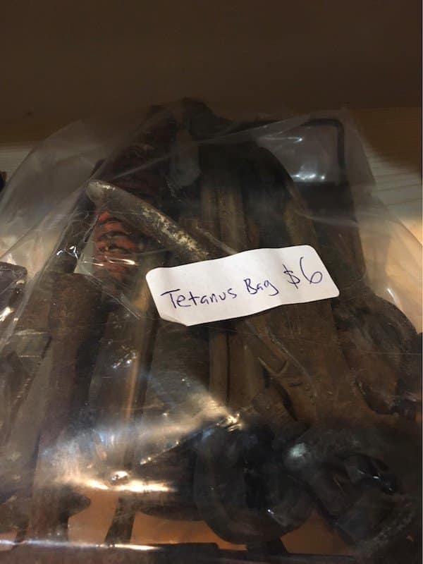 Plastic bag filled with rusty metal tools labeled simply as Tetanus Bag.