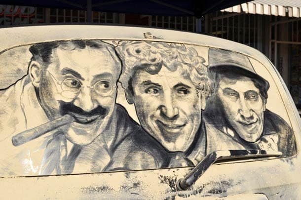 Realistic portrait of the Marx Brothers comedy trio drawn on a dirty car window.
