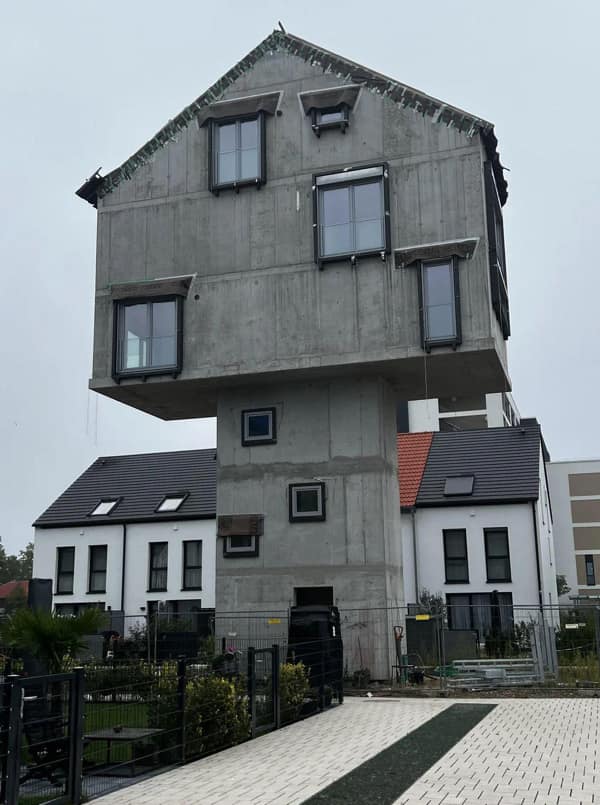 A massive diy fail showing a top-heavy concrete house that looks unstable.