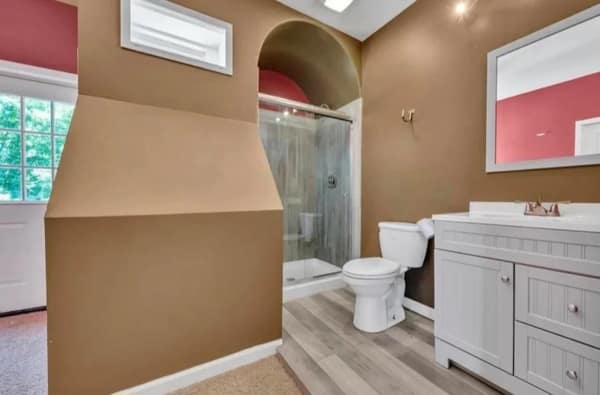 A bathroom diy fail featuring a strange brown wall arch and a glass shower.