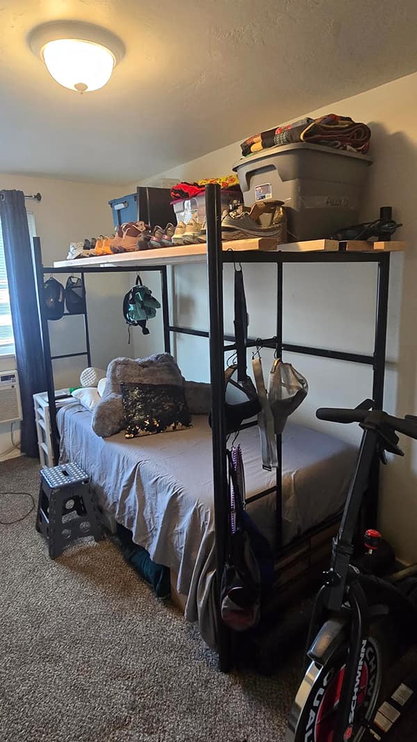 A bedroom diy fail where a bunk bed is built over a stationary bike and storage bins