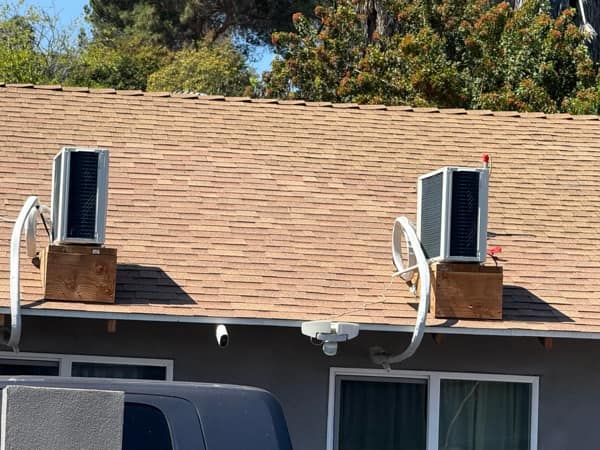 A dangerous diy fail showing AC units balanced on wooden blocks on a roof.