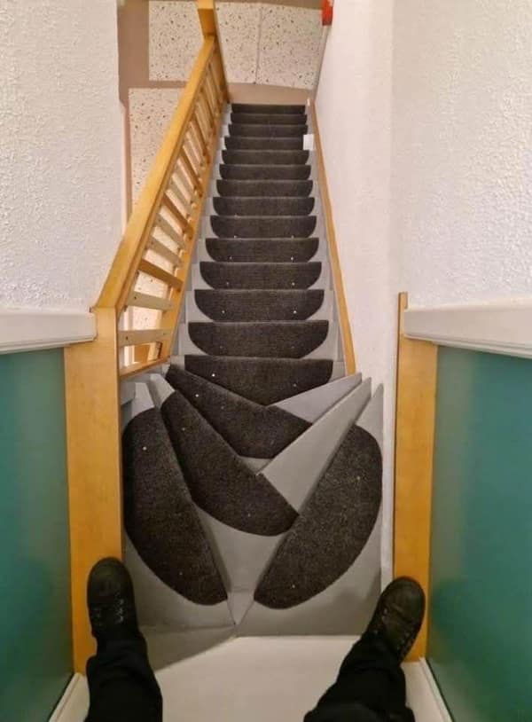 A carpeting diy fail on stairs where the chevron pattern is misaligned and chaotic.