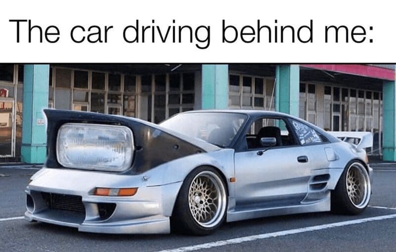 Silver sports car with pop up headlights looking like wide open eyes meme.
