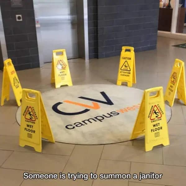 Circle of yellow wet floor caution signs arranged like a ritual in a building lobby.