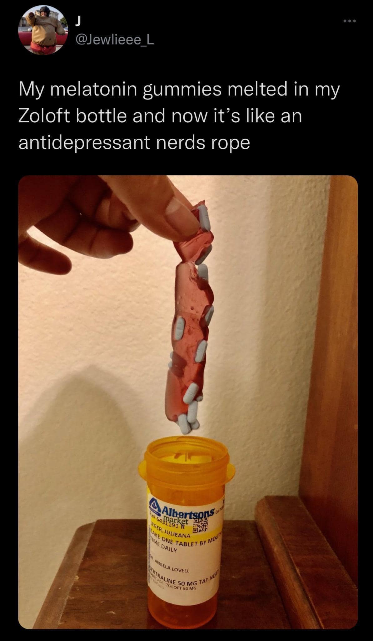 Long melted string of red melatonin gummies being pulled from a pill bottle.