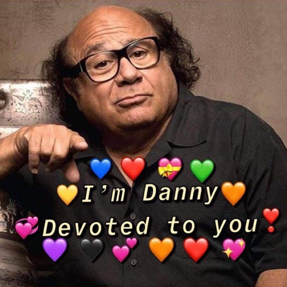 Danny DeVito pointing lovingly at camera surrounded by colorful heart emojis.