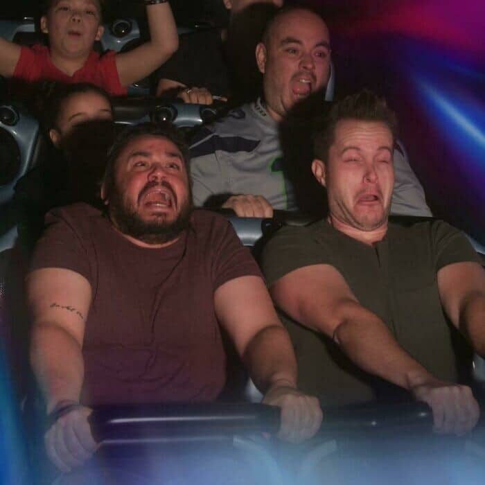 A funny rollercoaster picture of two men in the front row of Space Mountain, making hilarious, pained G-force faces.