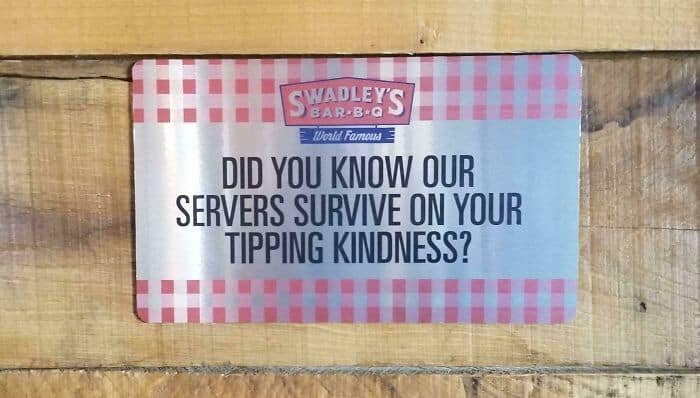 Restaurant sign admitting servers rely on tips to survive financially instead of wages.