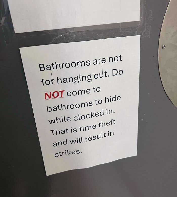 Bathroom sign forbidding employees from hiding while clocked in to avoid time theft.