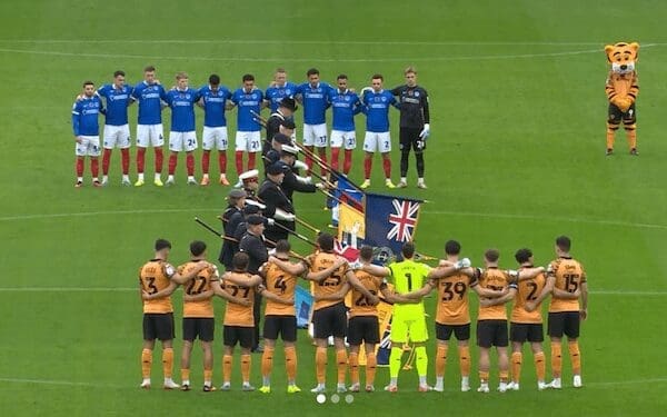 A lone tiger mascot stands awkwardly to the side while two football teams observe a moment of silence.