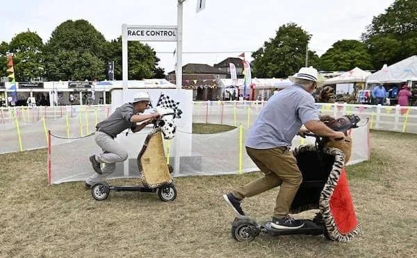 A funny meme of two men racing on mobility scooters that are decorated like Only Fools and Horses vehicles.