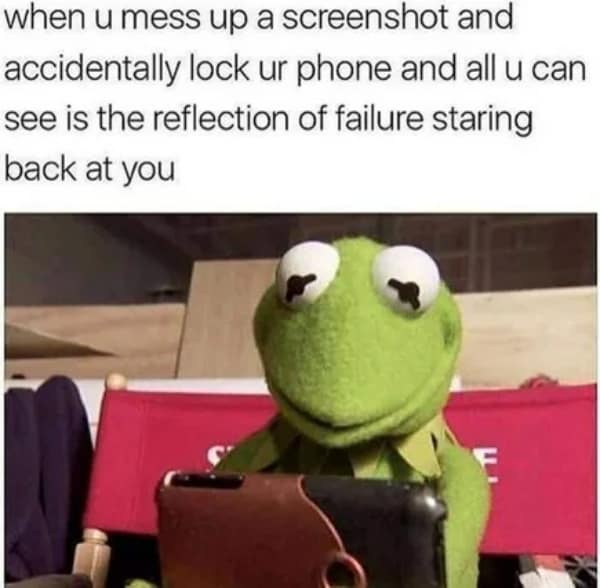 Kermit staring blankly at a phone screen seeing his own reflection in the dark.