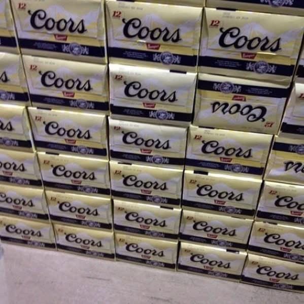 A perfectly stacked wall of Coors beer cases, ruined by one single box being placed upside down.