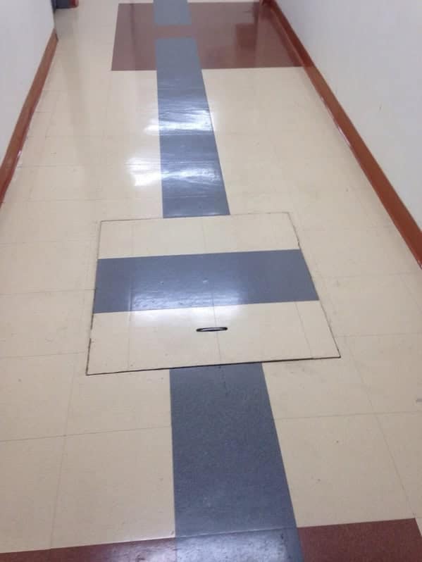 A floor access panel that was put back incorrectly, breaking the clean, painted line on the hallway floor.