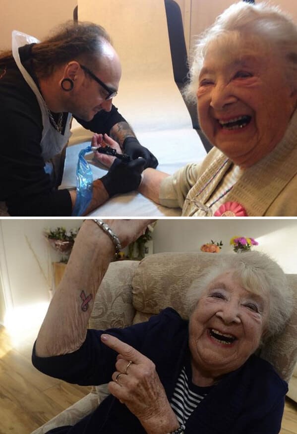 A very happy, elderly woman laughing while getting her first tattoo: a small, pink breast cancer ribbon.