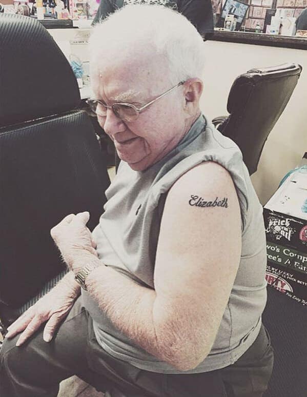 A sweet, elderly man smiling at his new, simple "Elizabeth" name tattoo on his shoulder.
