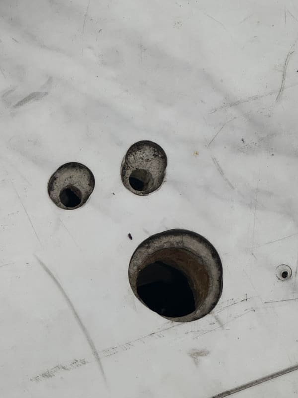 White metal panel with three holes arranged to look like a shocked face.