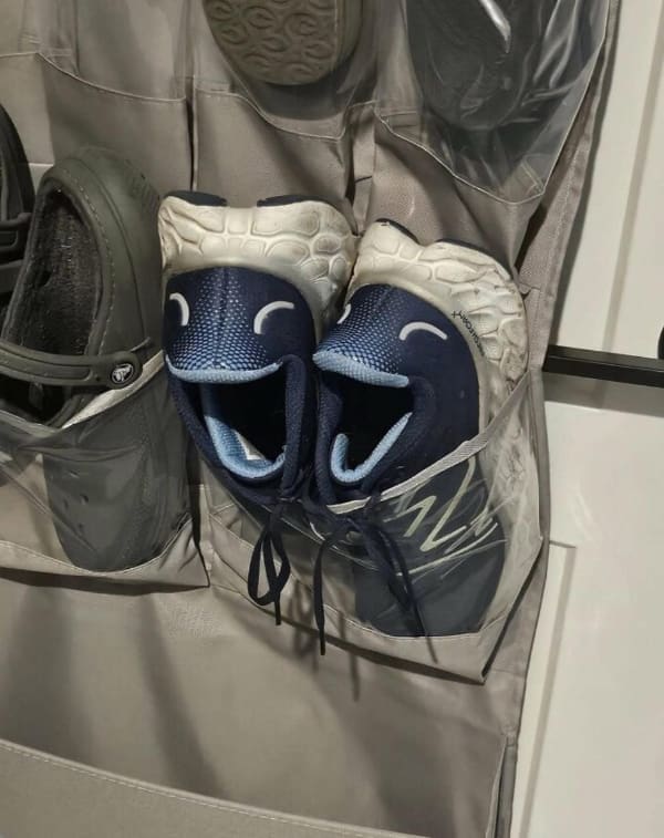 Pair of blue running shoes in a hanging organizer looking like smiling faces.