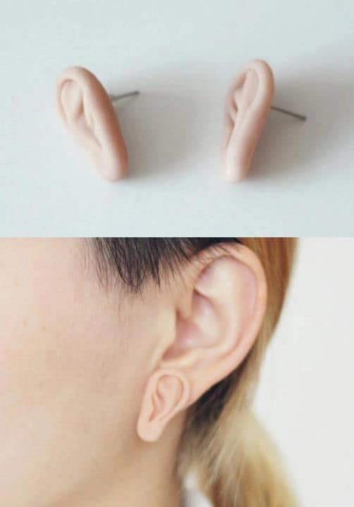 Creepy and weird stud earrings shaped like tiny, realistic human ears worn below the real ear.
