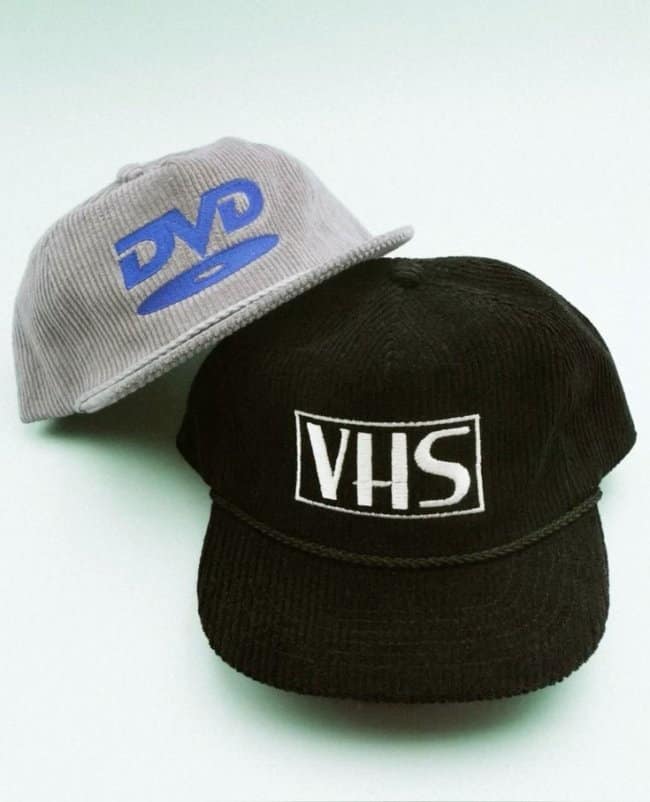 A pair of nostalgic retro-themed corduroy hats with embroidered VHS and DVD logos.